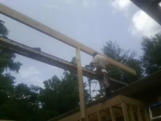Carpenter setting a ridge beam over a new addition frame — Ice Dam Removal by Roofing Brothers in Harrietta