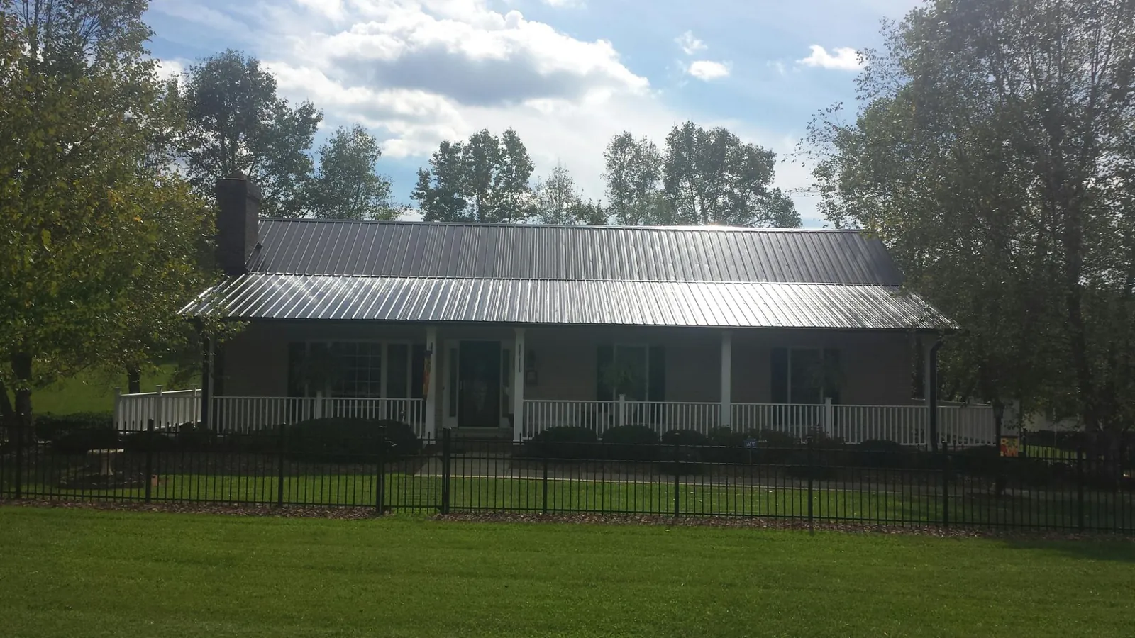 Gray metal roof on a brick ranch with a full width front porch — Gutter Guard Installation work by our crew in Harrietta